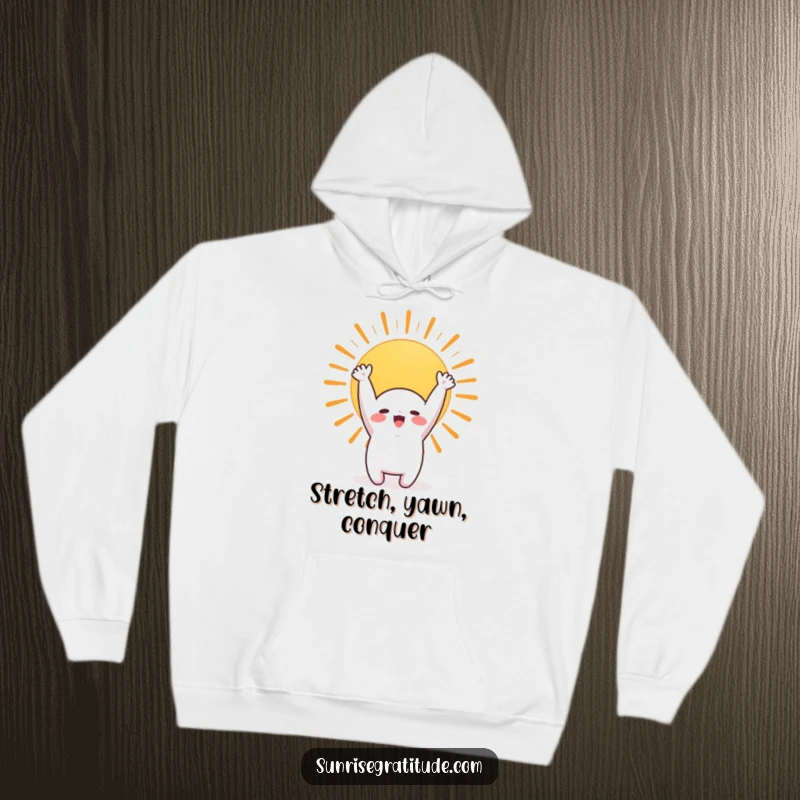 Funny hoodie depicting a cute character joyfully stretching towards a beautiful rising sun, cozy and cheerful.