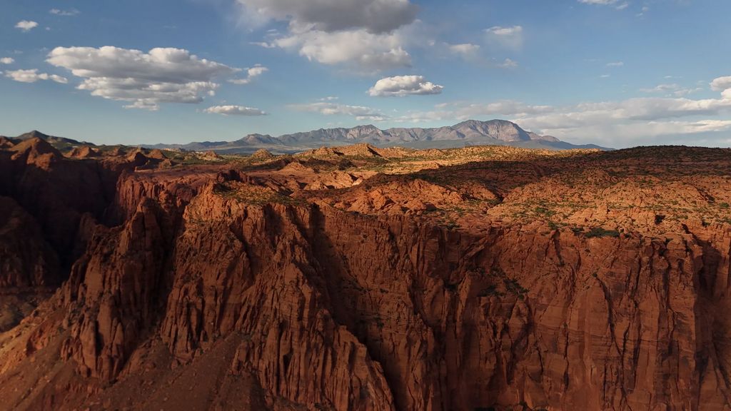 Aerial view over red rock canyon country with mountains in the distance near Ivins, Utah